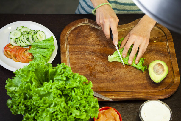 Woman cuts the salad on wooden cutting board. flat lay - Foto, Imagen