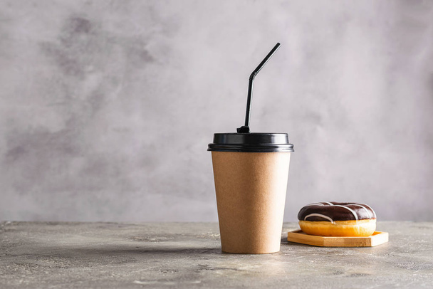 Papieren beker met koffie of thee donut in chocolade glazuur op een grijze achtergrond. Zero West-voedsel- en drankconcept. - Foto, afbeelding