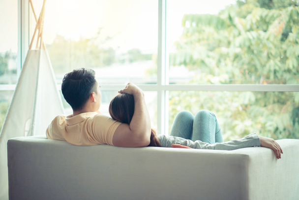 Happy couple sitting on the sofa and being a man embracing his girlfriend with love in the living room and relax. Concept of romantic on valentine day. Proposal and marriage - Foto, imagen