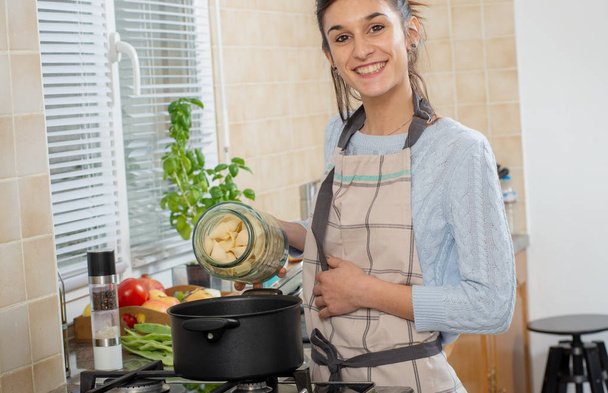 a pretty young brunette woman cooking in the kitchen - Photo, Image