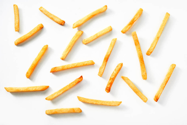 Scattered thin straight fried potato chips on a white background viewed from above - Фото, изображение