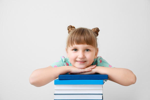 Χαριτωμένο κοριτσάκι με βιβλία στο φως φόντο - Φωτογραφία, εικόνα