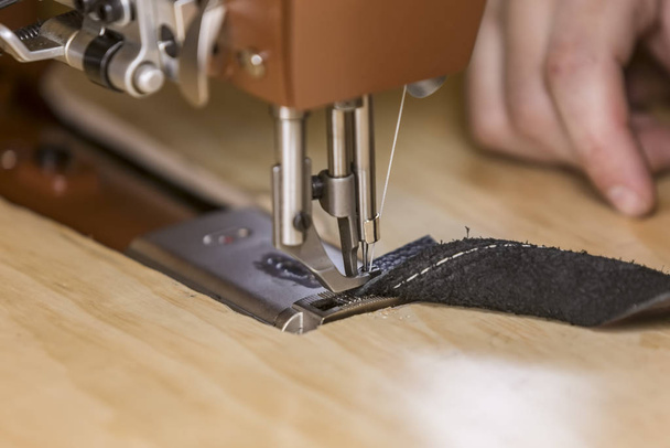 Zwarte lederen strip op een commerciële naaimachine met suède zijde - Foto, afbeelding