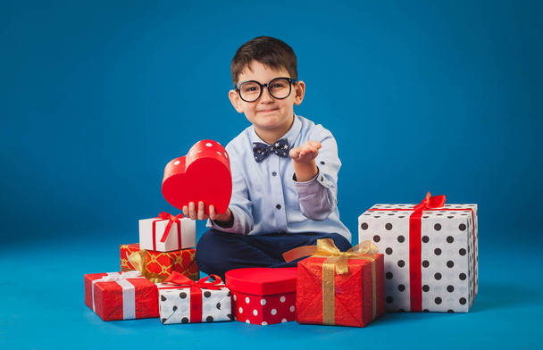 Cute kid with gifts on the blue background - Foto, imagen