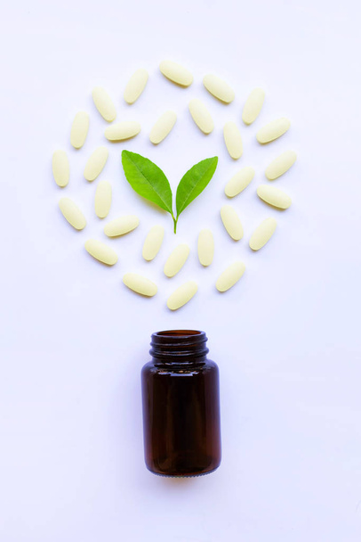 Vitamin C bottle and pills with green leavs on white background. - Foto, Imagen