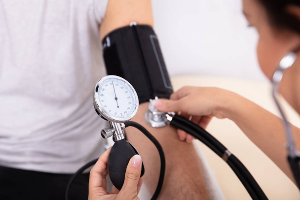 Close-up Of Doctor Measuring Blood Pressure Of Male Patient - Foto, Imagen