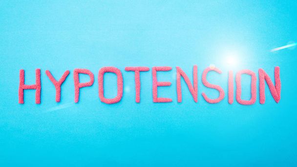 Word hypotension from red letters on a blue background. Arterial hypertension disease concept, medical, inscription - Fotó, kép