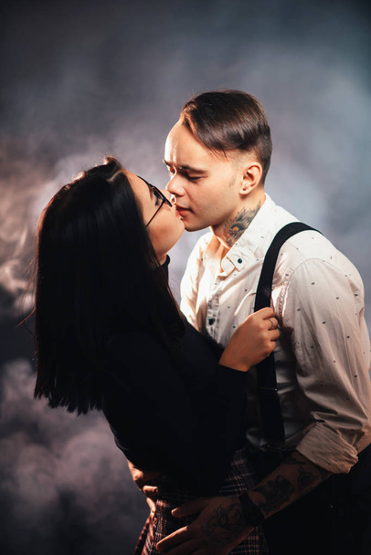 Couple in fashionable clothes on a dark smoky background. - Fotografie, Obrázek
