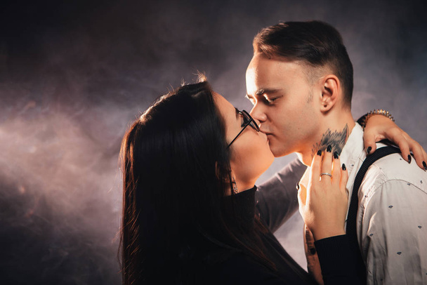 Couple in fashionable clothes on a dark smoky background. - 写真・画像