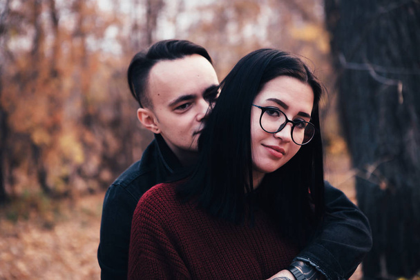 young man and young woman are sitting on a plaid in an autumn forest. - Fotografie, Obrázek