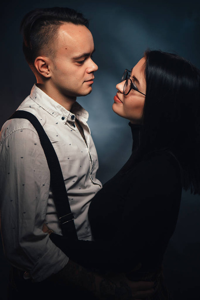 Couple in fashionable clothes on a dark background with smoke. - Valokuva, kuva