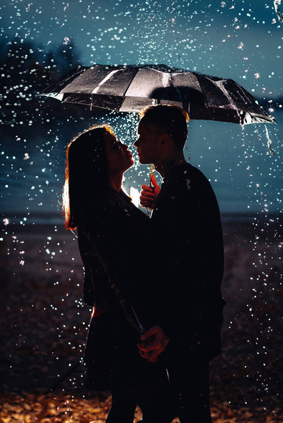 young man and woman under an umbrella and rain. - Foto, afbeelding