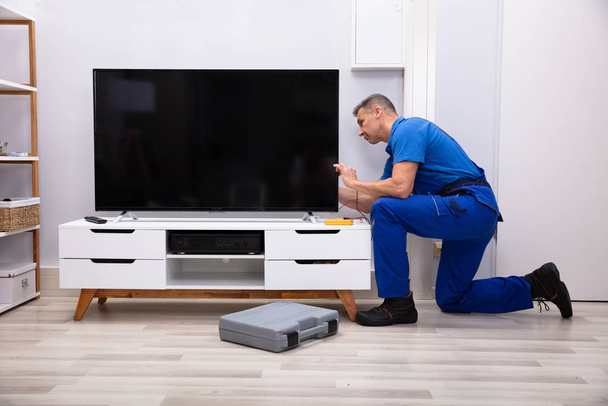 Male Technician Repairing Television With Digital Multimeter At Home - Φωτογραφία, εικόνα
