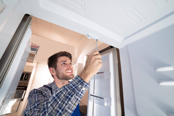Young Male Technician Checking Refrigerator With Screwdriver - Photo, image