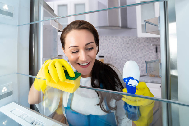 Close-up Of A Happy Young Woman Cleaning Refrigerator With Sponge - Foto, Imagem