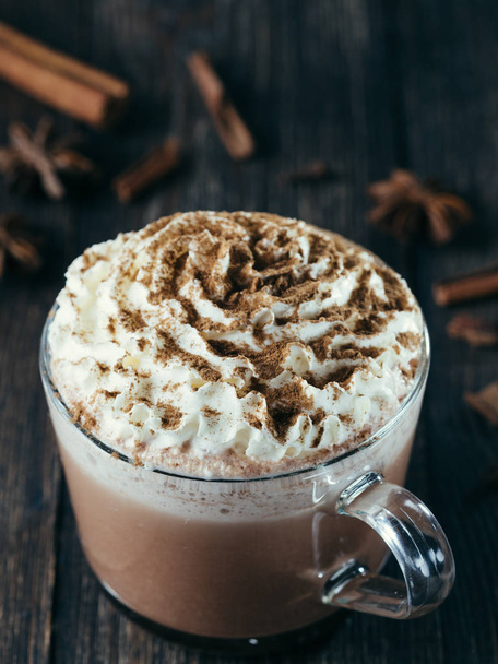 Glass cup with hot chocolate, whipped cream and cinnamon powder. - Foto, Bild