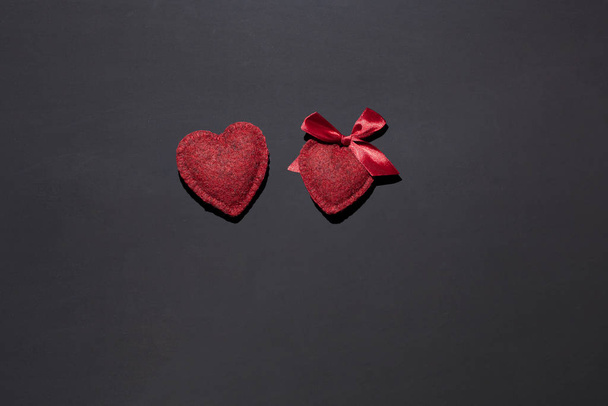 two hearts on a black background, bow on one, concept of couple, love, declaration of love, surprise for St. Valentine's Day - Photo, image
