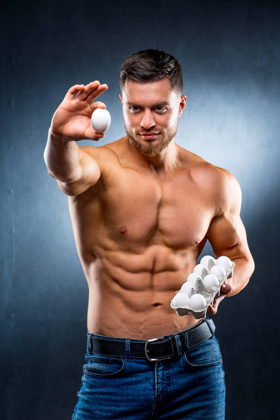 Sportsman is holding a packaging with eggs. Bodybuilder and natural protein. Healthy lifestyle concept. - Fotoğraf, Görsel