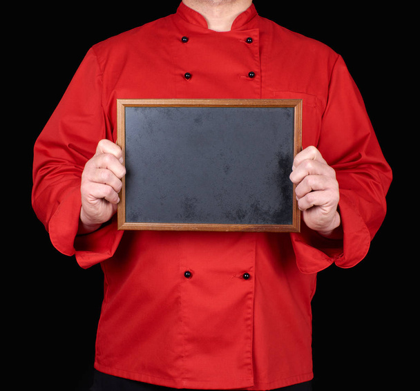 chef in red uniform holding an empty wooden frame with black background - Foto, Imagem