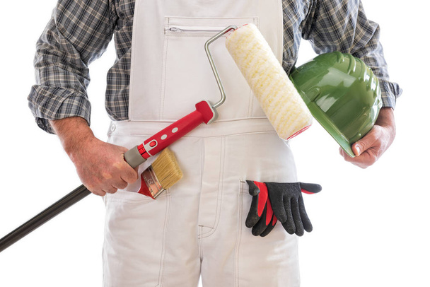 House painter worker with white work overalls, holds in his hand the roller to paint. Equipped with protective gloves. Isolated on white background. - Фото, изображение