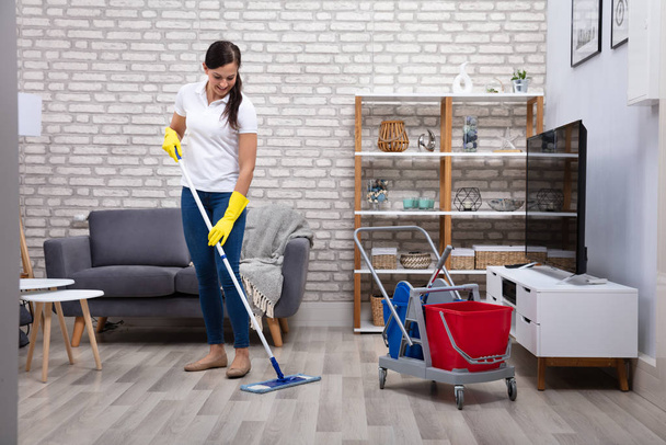 Female Janitor Cleaning Floor With Mop In Living Room - Фото, изображение