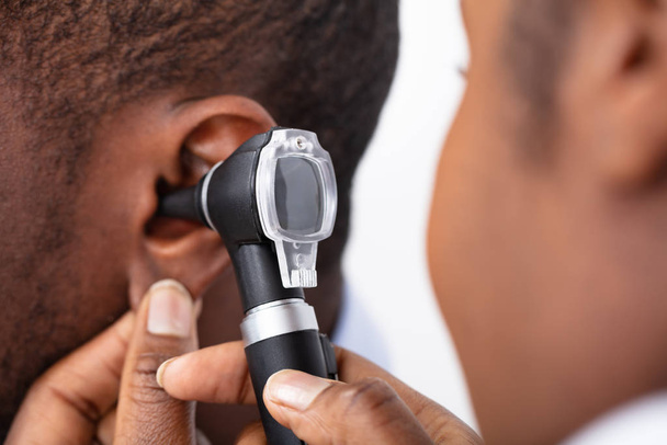 African Doctor Examining Male Patient's Ear With Otoscope - Φωτογραφία, εικόνα