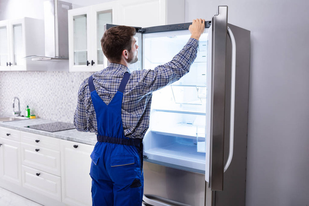 Serviceman Checking Temperature Of Refrigerator In Kitchen - Foto, imagen