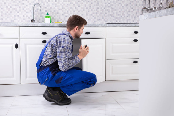 Crouching Repairman Fixing The Door Of Kitchen Sink - Foto, Imagem