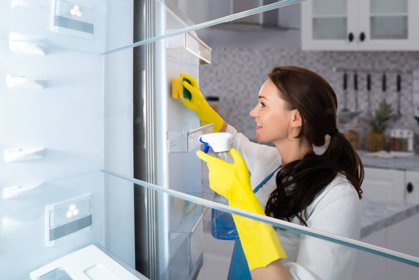 Close-up Of A Happy Young Woman Cleaning Refrigerator With Sponge - Foto, immagini