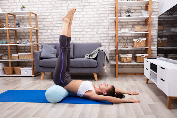 Young Woman Doing Stretching Exercise On Blue Yoga Mat - Foto, imagen