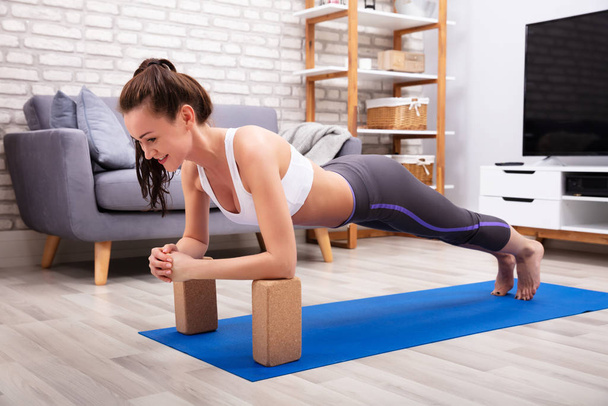Fit Young Woman Using Wooden Blocks While Doing Exercise On Yoga Mat - Фото, зображення