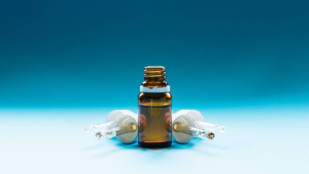 cosmetology, glass bottles with pipettes and cosmetic on a blue background - Foto, afbeelding