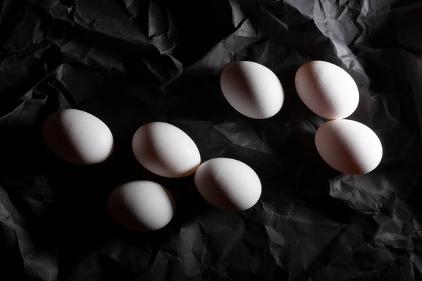 Seven white eggs on a dark background for coloring. - Фото, изображение