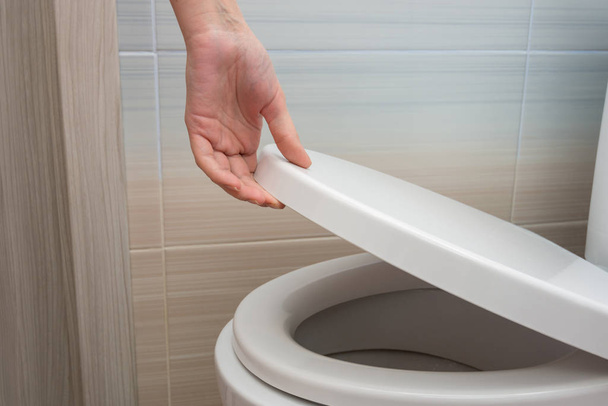 The hand closes or opens the toilet lid - Valokuva, kuva