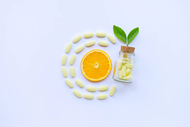 Vitamin C bottle and pills with orange fruit on white background. - Fotoğraf, Görsel
