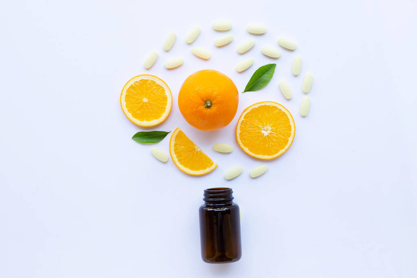 Vitamin C bottle and pills with orange fruit on white background. - Photo, Image