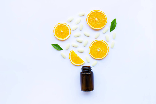 Vitamin C bottle and pills with orange fruit on white background. - Foto, immagini