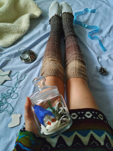 Nuori leikkisä tyttö sängyllä lämpimissä neulotuissa sukissa pitää lasia
  - Valokuva, kuva