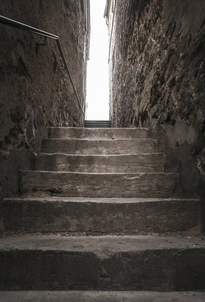 Aged stone stairs, between two old buildings, going up, toward the light, in Luxembourg city. Strong light at the end of the shadowy staircase. - Photo, image
