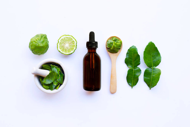 Bottle of essential oil and  fresh kaffir lime or bergamot fruit with leaves isolated on white background. - Foto, imagen
