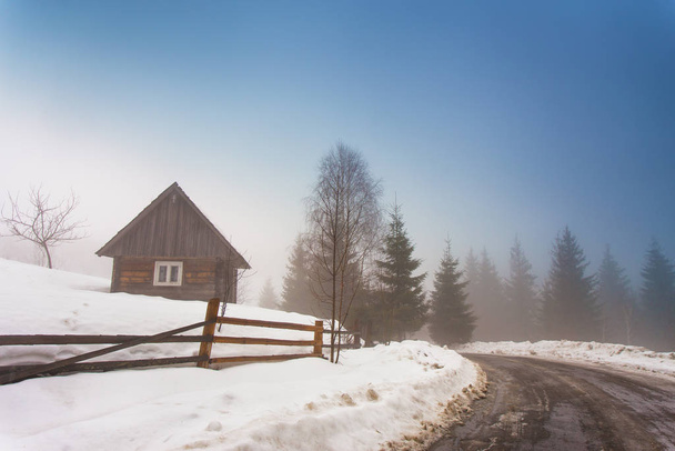 Lone house in mountain village. Foggy weather and melting snow on mountain country road in Carpathians. Weather forecast for early spring. Spring coming - Foto, immagini