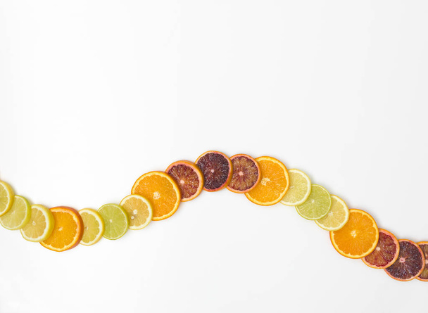 many fresh and healthy orange slices, zironen slices, lime slices, kumquat slices are nicely arranged on a white background - Photo, Image