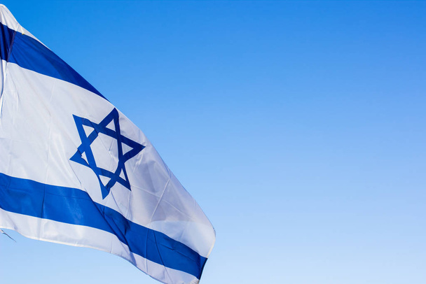 Israeli white and blue national flag with star of David evolving on a wind on empty sky background with space for copy or text, political sign and symbols concept picture - Fotografie, Obrázek