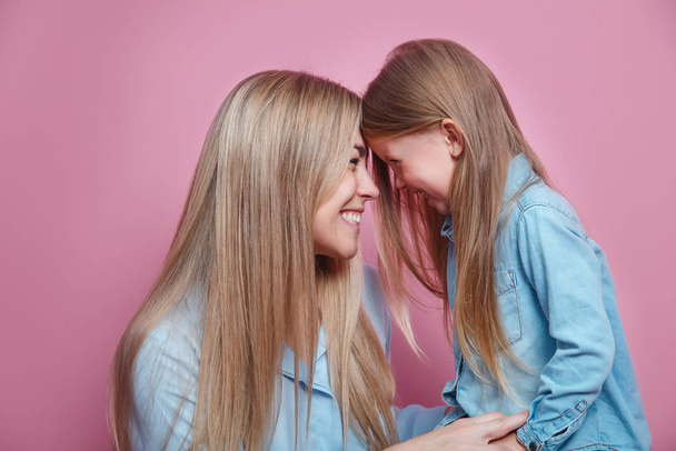 Onnellinen äiti nauraa hyväillen koskettava nenä hänen söpö tytär vaaleanpunainen tausta
 - Valokuva, kuva