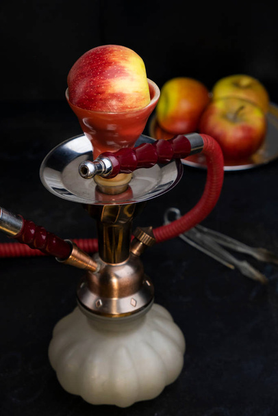 Red classic turkish arabian smoking oriental hookah shisha kalian with apple flavor on black background  - Photo, Image