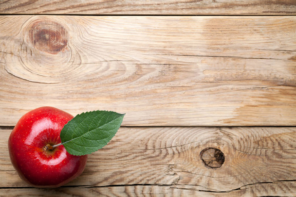Red apple with green leaf on wooden table. Top view - Foto, immagini