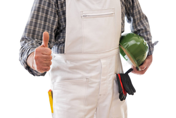 Construction worker in white work overalls with thumb up. Equipped with protective helmet. Isolated on white background. Construction industry. - 写真・画像