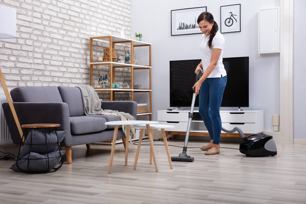Happy Young Female Janitor Cleaning Floor With Vacuum Cleaner - Foto, immagini