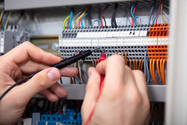 Close-up Of A Male Electrician Examining Fuse Box With Multimeter - Foto, immagini