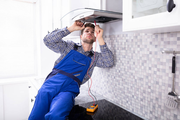 Handyman Checking Kitchen Extractor Filter With Multimeter In Kitchen - Foto, immagini